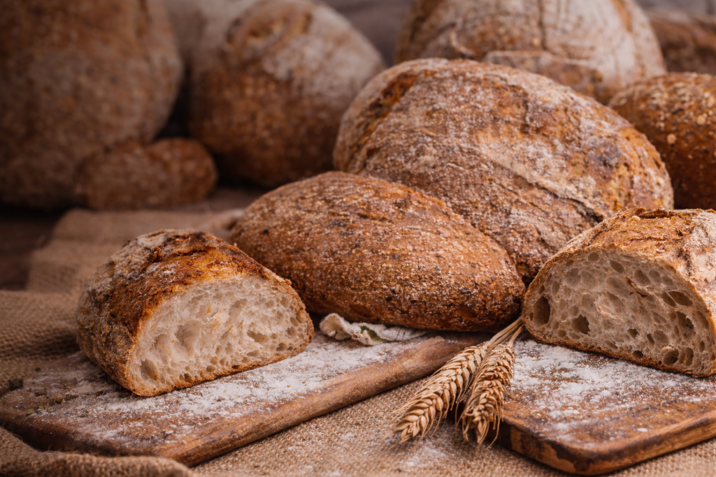 Pan de masa madre en Sevilla centro recién horneado sobre tabla de madera con corteza crujiente y miga alveolada artesanal.